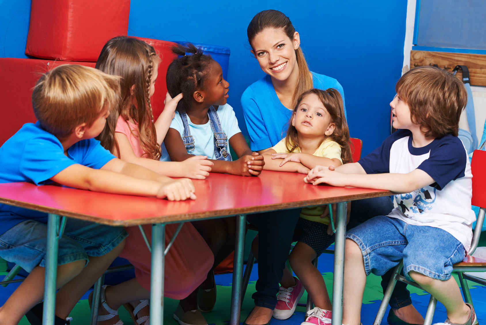 Gruppe Kinder sitzt mit Praktikantin im Kindergarten